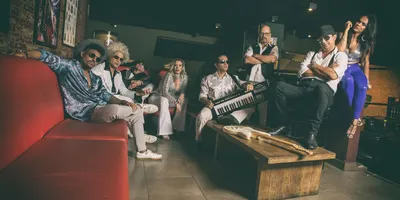 A banda reunida no sofá vermelho do camarim