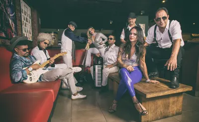 A banda no sofá vermelho, guitarrista sentado com o instrumento