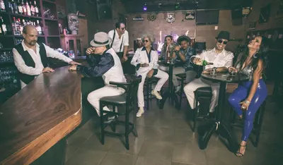 Cena de bar com a banda nas mesas altas e o balcão