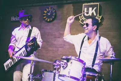 Baterista girando a baqueta ao lado do percussionista nas congas