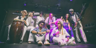 A banda completa no palco, ângulo baixo e panorâmico