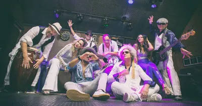 A banda no palco em poses descontraídas