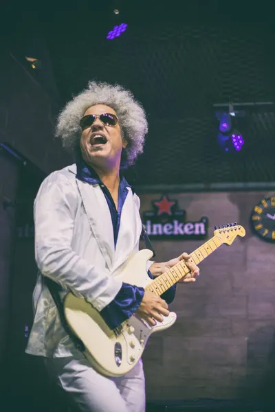 Guitarrista de peruca afro grisalha tocando em ângulo baixo