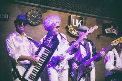 Keytar, guitarra e baixo lado a lado sob luz roxa