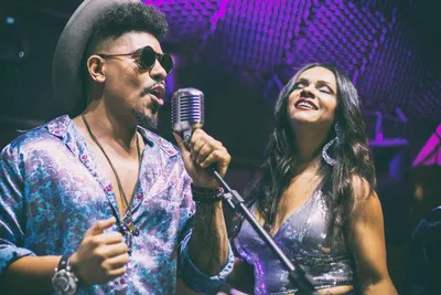 O vocalista principal cantando ao microfone vintage ao lado de uma backing vocal