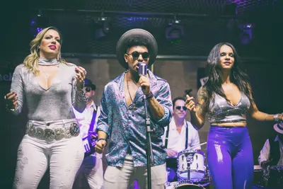 Trio de vocalistas dançando lado a lado no palco